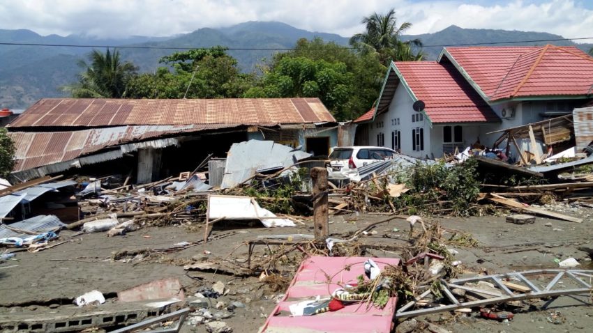 A scene of destruction depicts a toppled building with a partially collapsed roof and debris scattered across a residence.