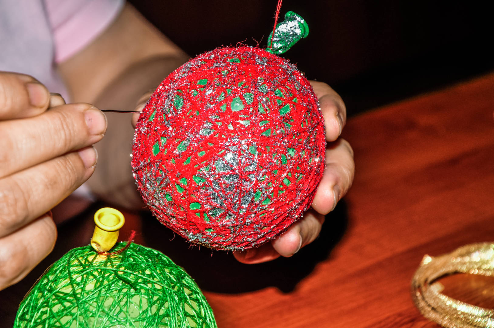 Christmas Crafts from Around the World Hands work on an ornament made from a balloon and yarn.
