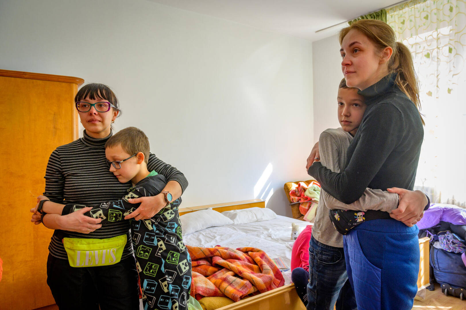 Two sisters, both moms, are hugged by their sons as their eyes fill with tears.
