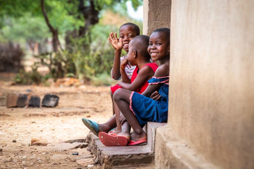 Children laugh while sitting on a stoop.