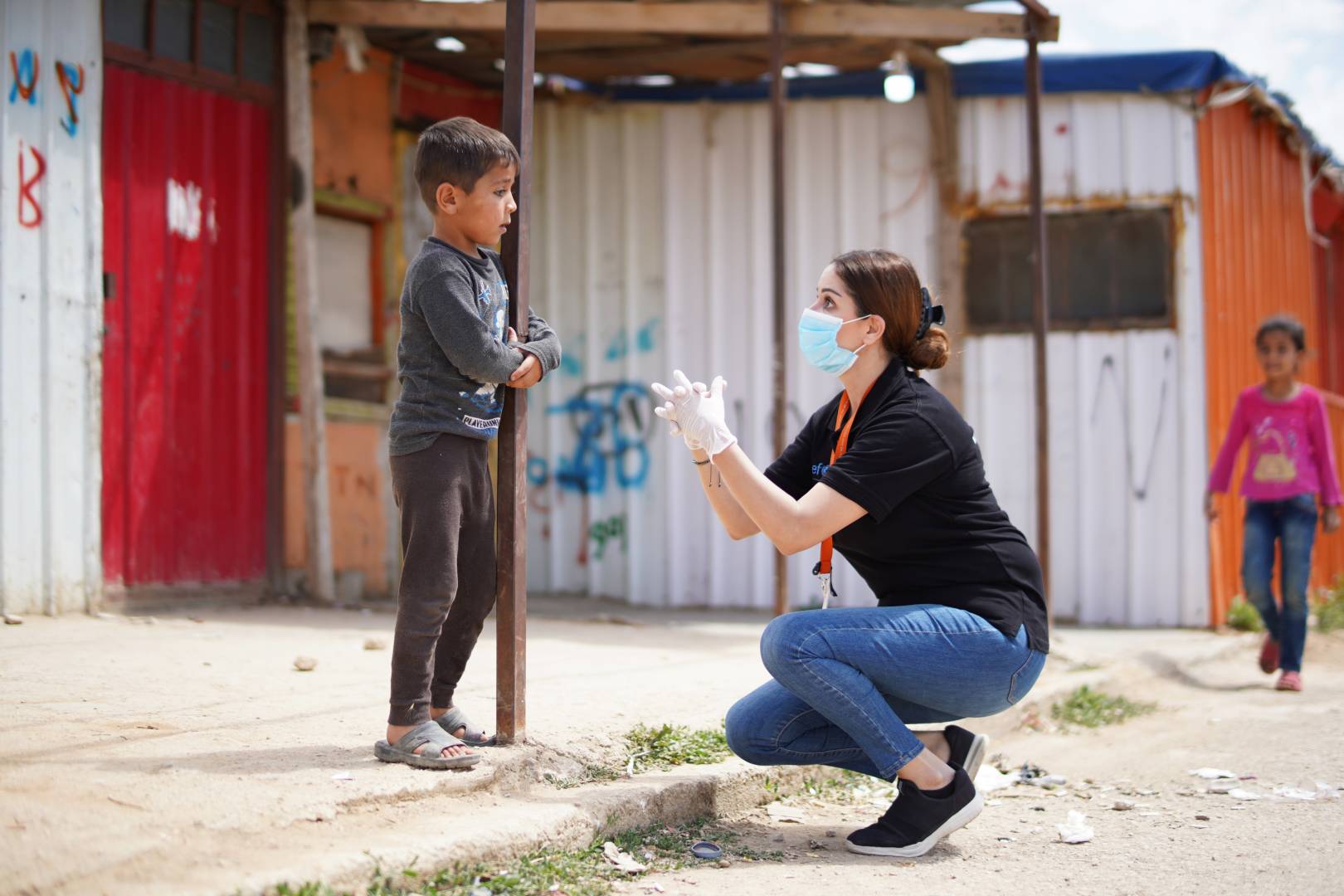 An aid worker teaches a boy how to wash his hands.
