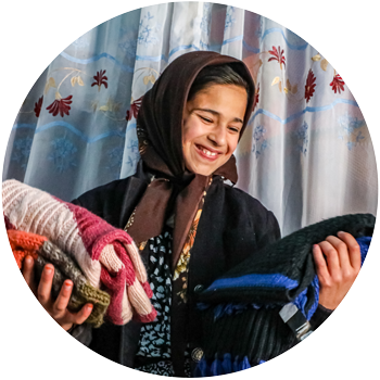 Girl holds donated sweaters.